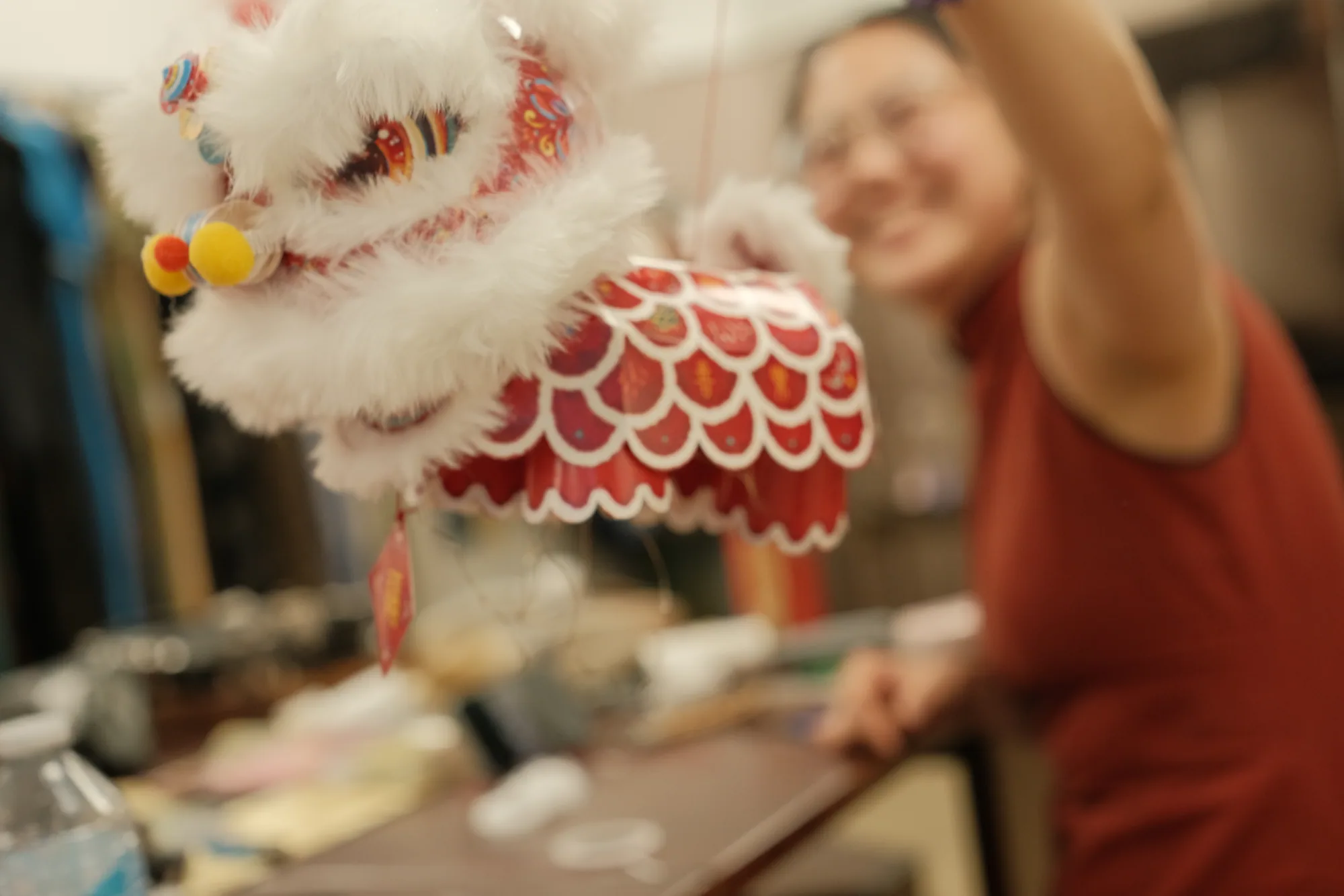 A lion dance figure in the foreground with a smiling participant behind it